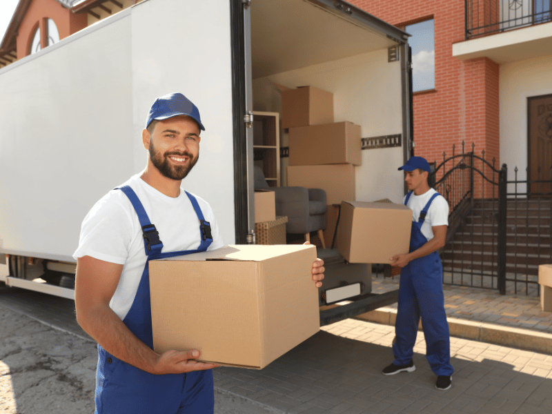 Two guys moving boxes and placing them into a moving truck