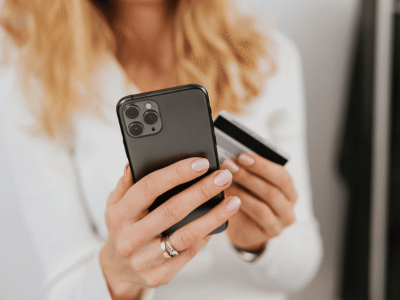 A women holding a mobile with a credit card in her hand
